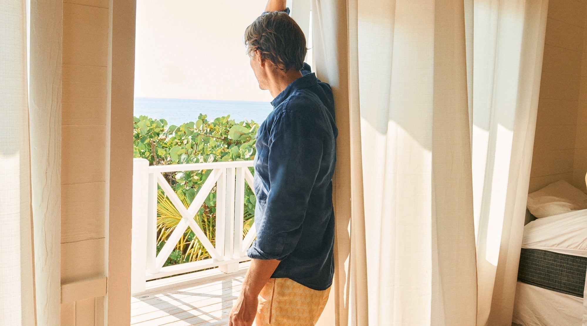 Model wears navy linen shirt with yellow Bermuda swim shorts