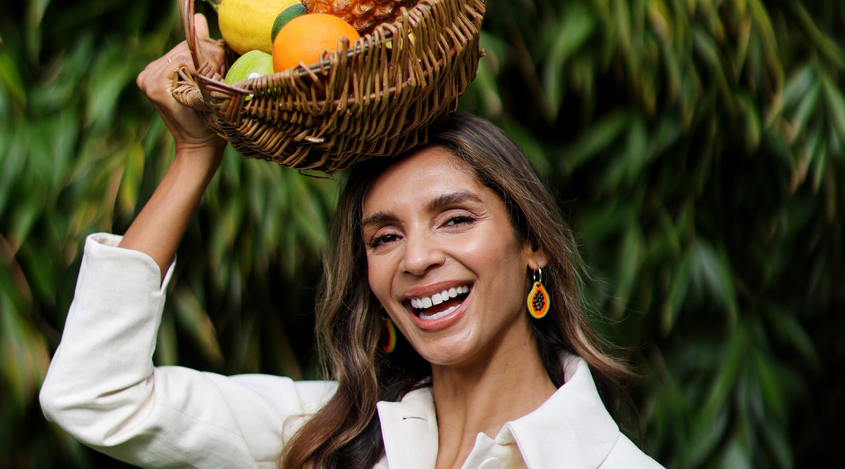Chef Shivi Ramoutar smiling holding a basket of fruit above her head