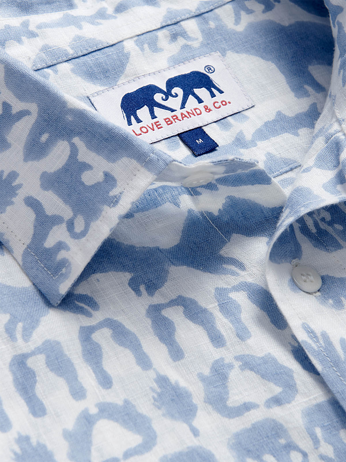 Close-up of unisex linen long sleeve shirt featuring 'Coexist' print in sky blue with various Indian jungle animals. The collar showcases the Love Brand & Co. label.