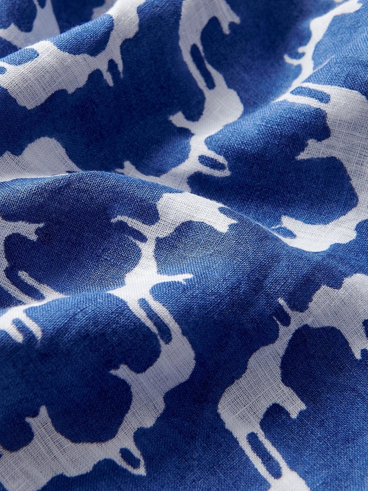 Close-up of blue linen fabric with a white block print pattern. Blue linen pants mens depicting Asian elephants, creating an illusion of Indian palaces.