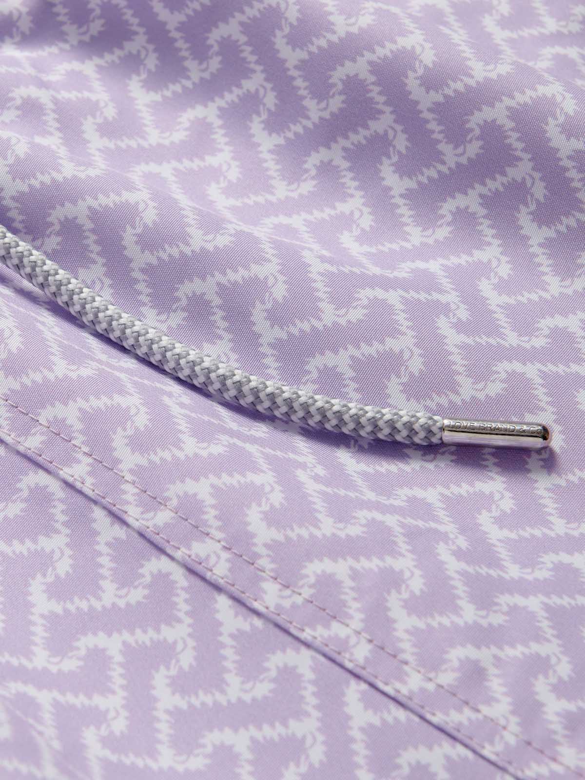 Close-up view of Boys Crazy Maze Staniel Swim Shorts by LOVE BRAND & Co. White and purple swimming shorts for kids with drawstring waist and pockets.