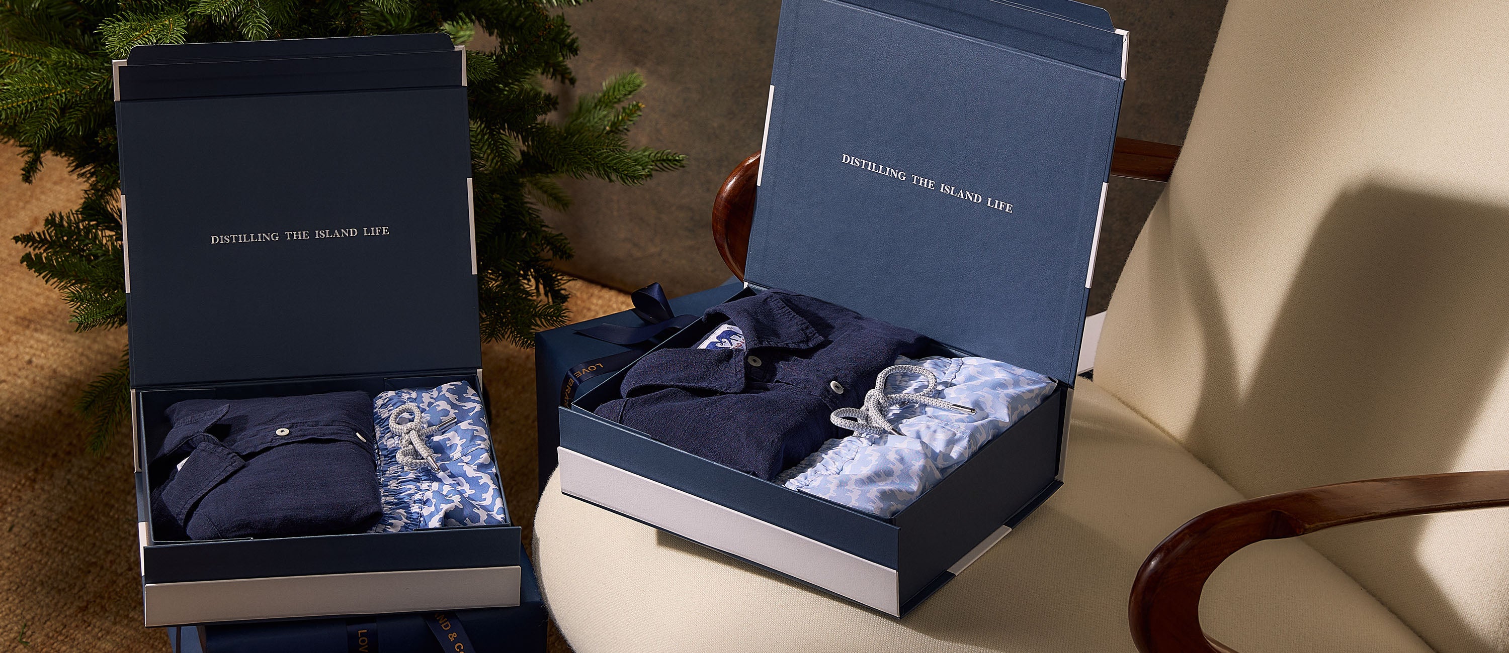 Two open blue boxes containing men's clothing on a beige surface with a blurred background
