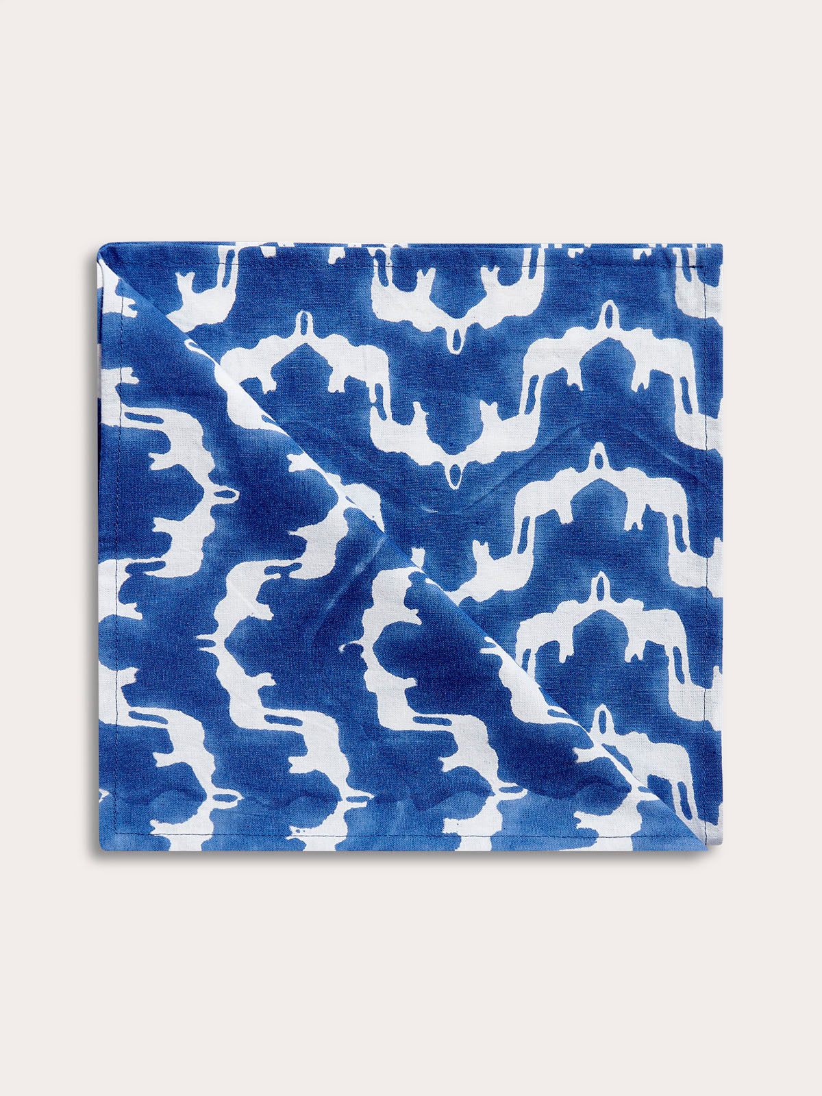 Cotton napkin from the "Elephant Palace Blue" set featuring a traditionally block-printed design of white Asian elephants forming an illusion of Indian palaces on a blue background.