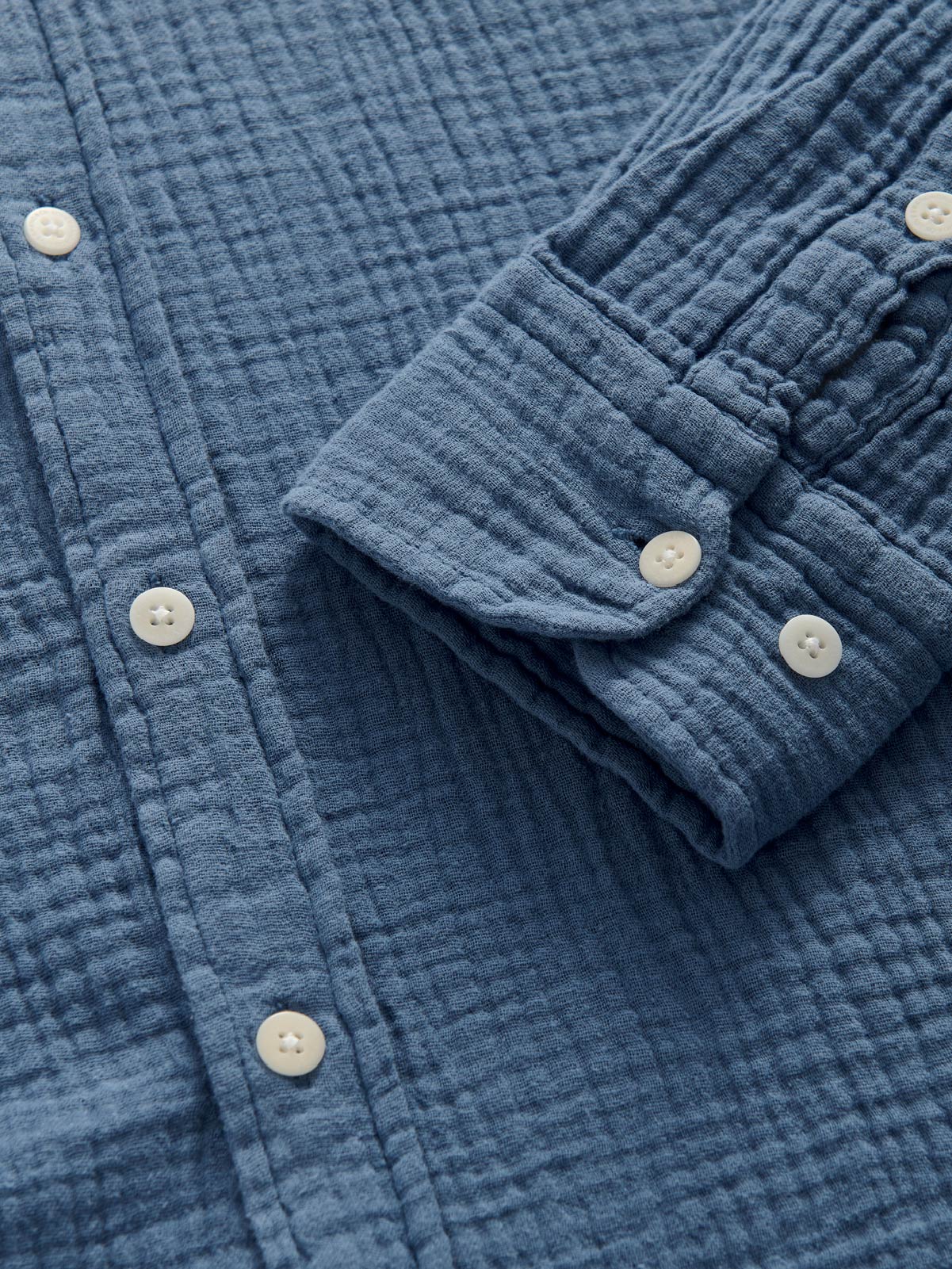 Close-up of a blue textured shirt with buttons