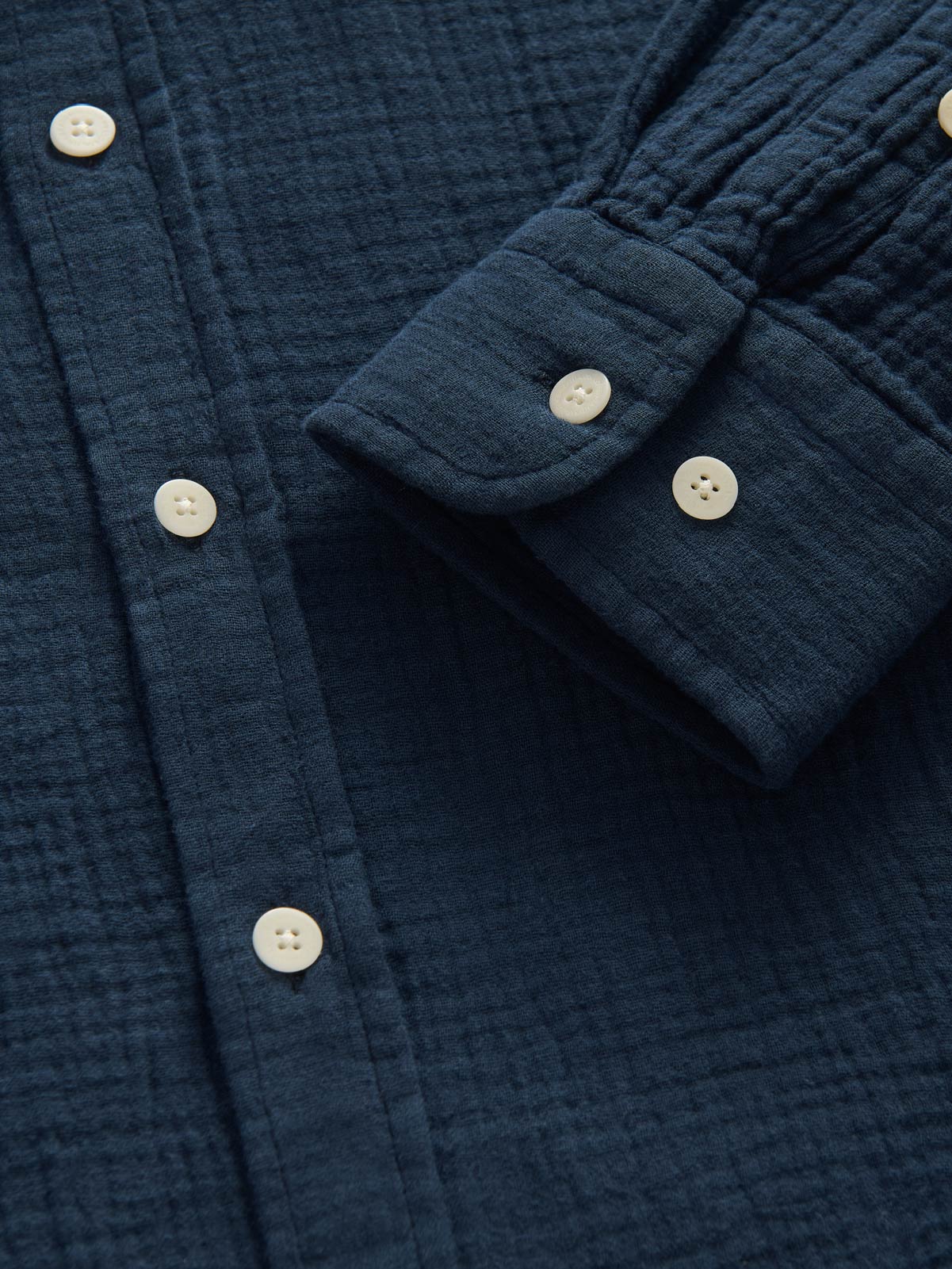 Close-up of a blue textured shirt with buttons