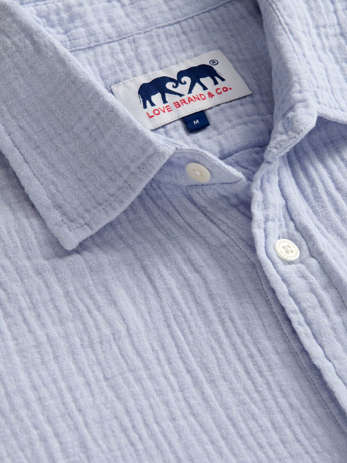 Close-up of a light blue corduroy shirt with a brand label on the collar.