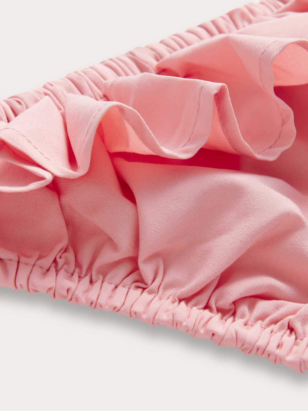 Close-up view of Girls Pastel Pink Calabash Bikini Bottoms. Pink fabric made from 100% recycled material.