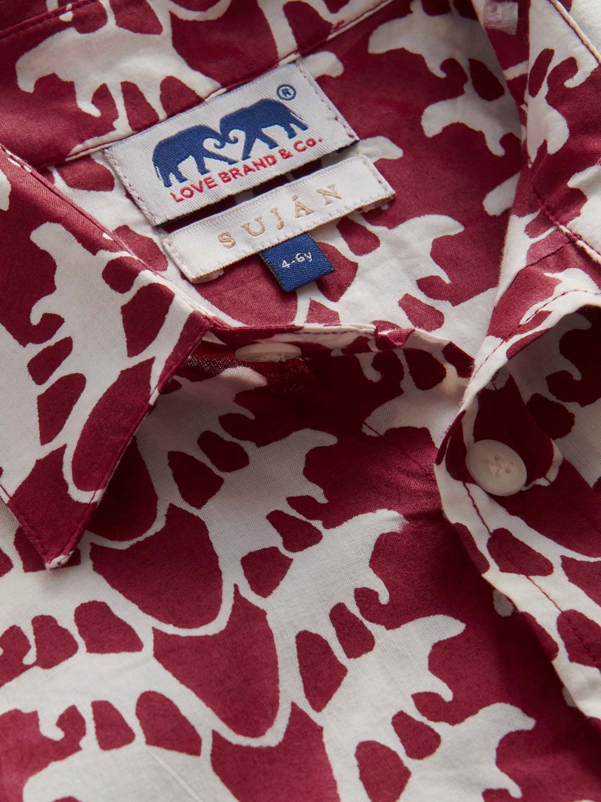 Deatiled view of Kids Lurking Leopards Abaco Cotton Shirt showing leopard pattern and SUJÁN Camps logo.