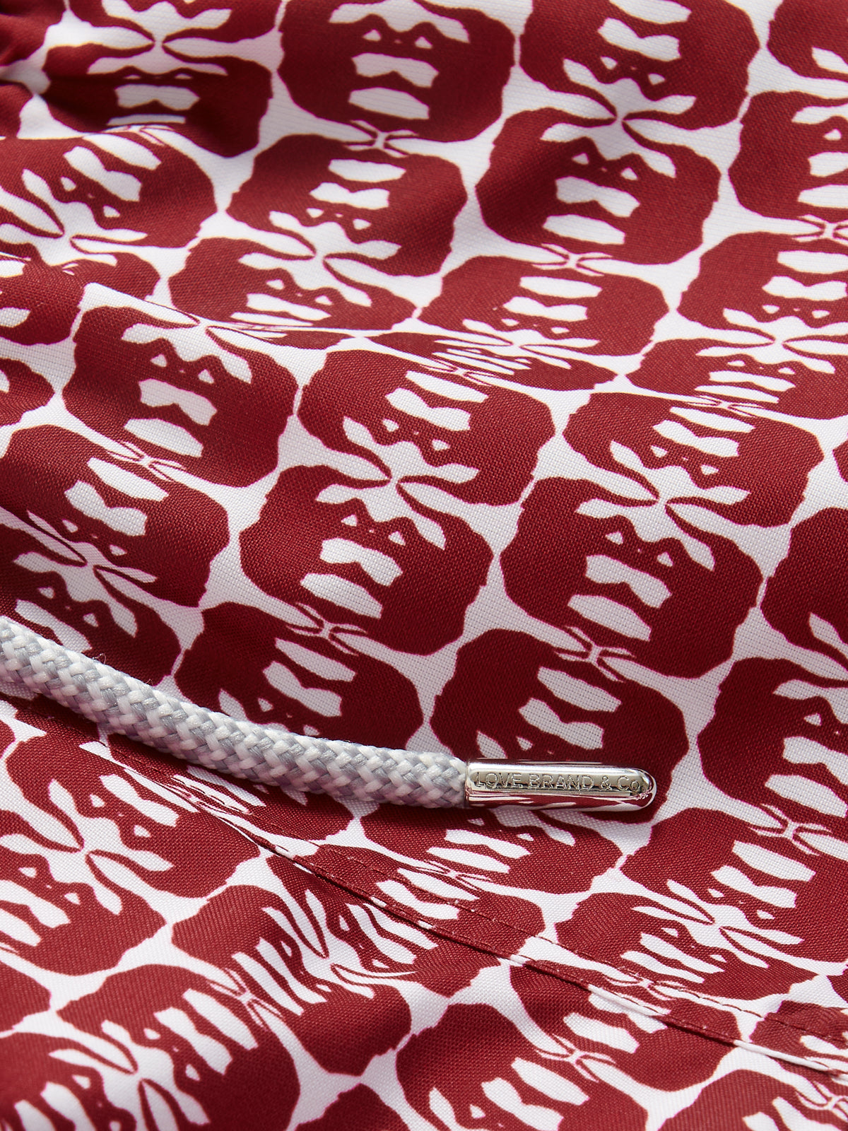 Boys Elephants of India Staniel Swim Shorts with deep burgundy elephant pattern on a white base, featuring a close-up of the fabric and drawstring detail.