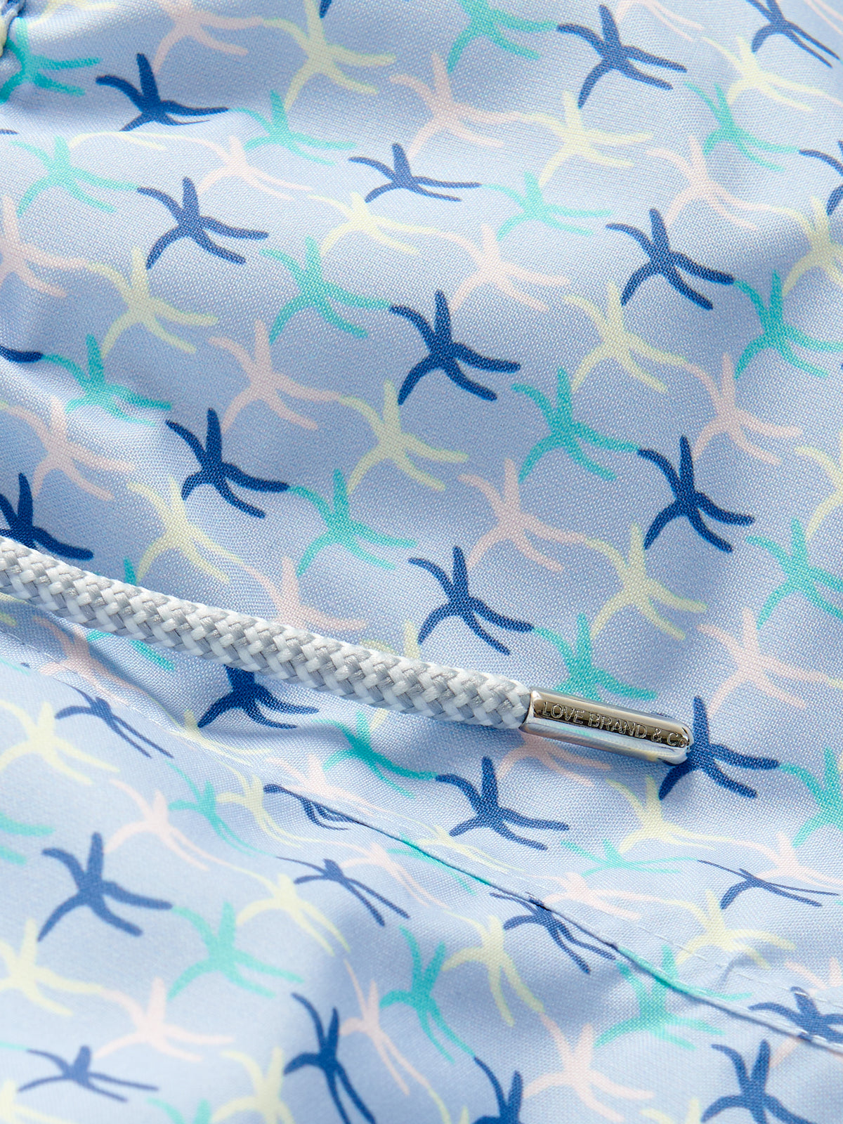 Close-up of Boys Star Dancer Staniel Swim Shorts featuring vibrant pastel sea star patterns in pink, limoncello, cay green, and ocean blue on quick-drying recycled fabric.