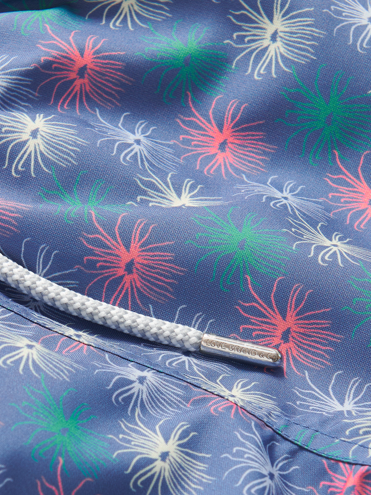 Close-up view of Boys Dont be Anemone Staniel Swim Shorts, showcasing colorful sea anemone patterns on blue fabric, with a white drawstring detail.