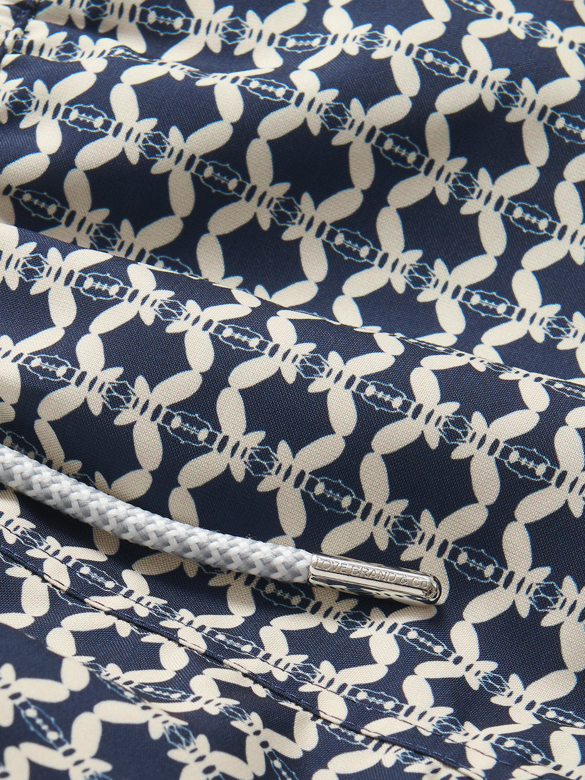 Close-up view of Boys Bee Propelled Staniel Swim Shorts featuring a unique stone-coloured bee print on a deep blue background made from 100% recycled materials.
