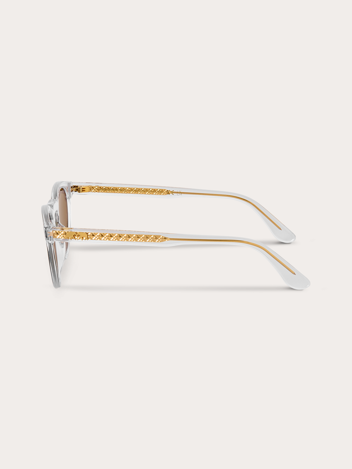 Side view of clear sunglasses with gold accents on a white background