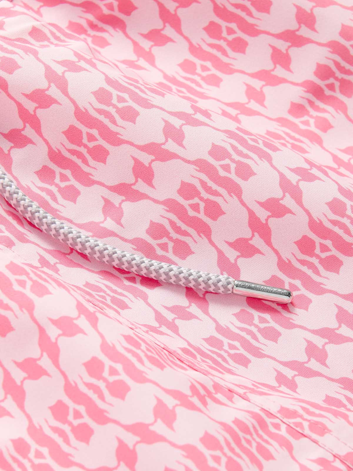 Close-up view of Boys Camel Mirage Pink Staniel Swim Shorts showcasing a bespoke camel pattern in pink and white. The drawstring cord is visible, highlighting the detailed design celebrating Cop28 in Dubai 2023 and UAE's environmental efforts.
