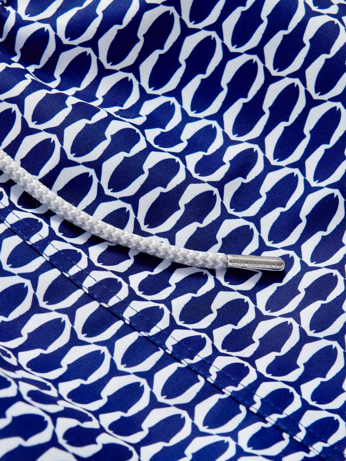 Close-up view of the Boys Pine Cay Fish Staniel Swim Shorts showcasing a sleek geometric print of blue and white fish silhouettes with a white drawstring.