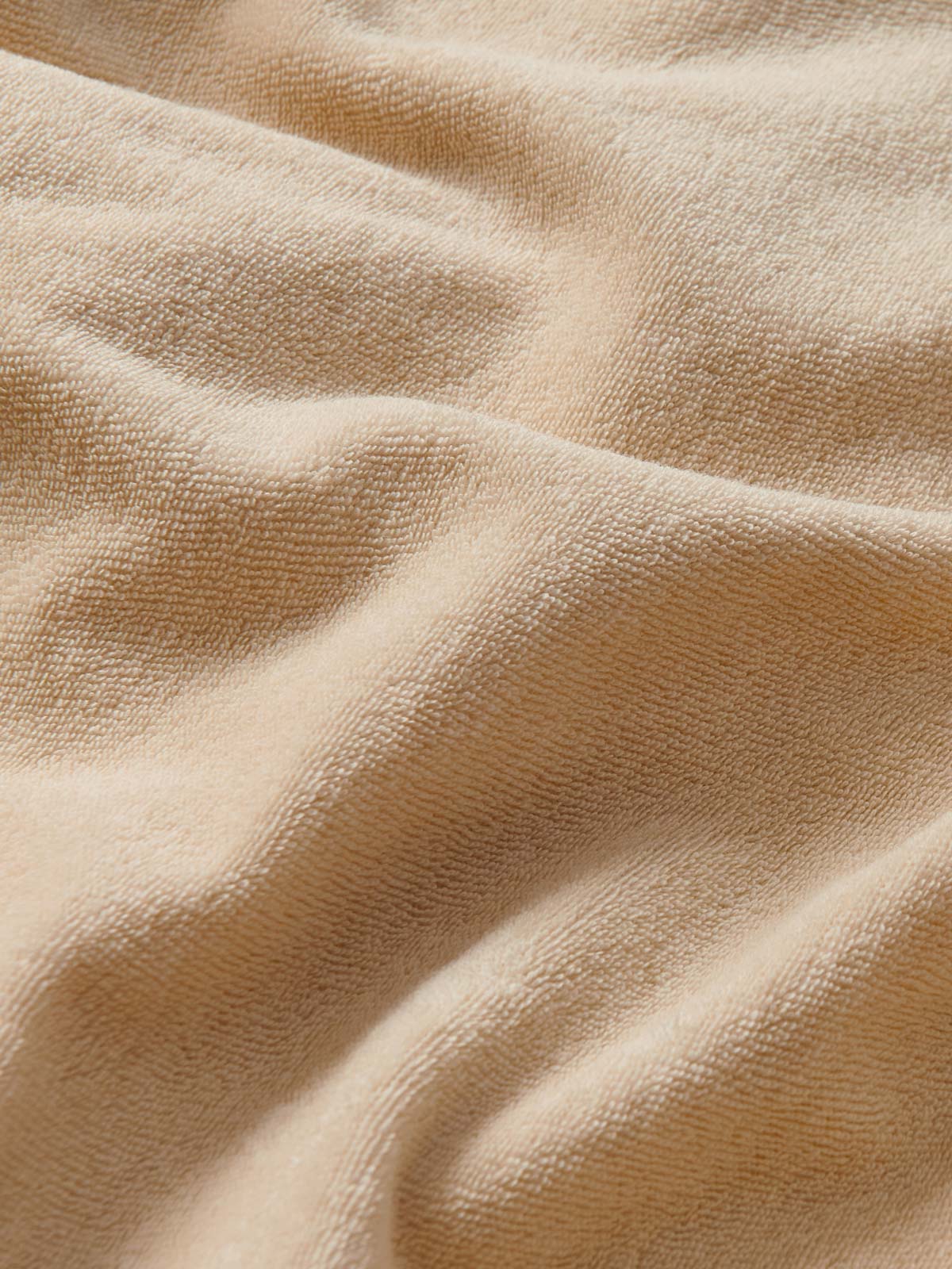 Close-up view of the cotton fabric of Men's Coconut Holmes Terry Shorts. Beige 100% cotton shorts with 2 front pockets. Terry towelling shorts with elastic waist and drawstring tie.