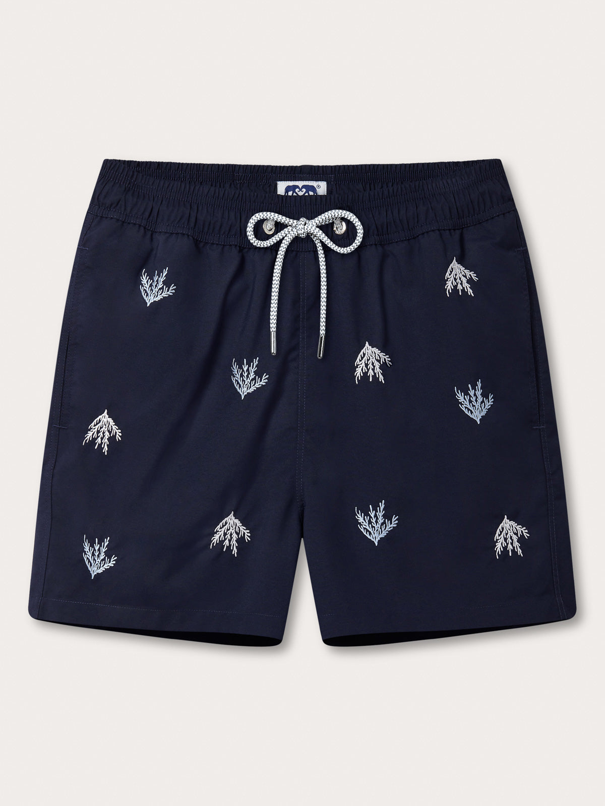 Navy swimming shorts with white embroidered patterns on a light grey background