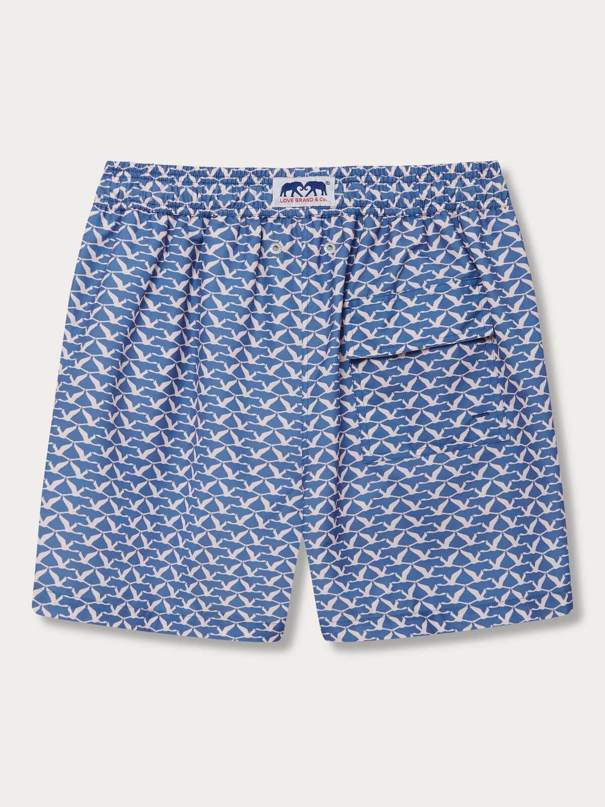 back view of our mens swim shorts Flamingo Flamboyance featuring a pastel print flamingo pattern on a blue background