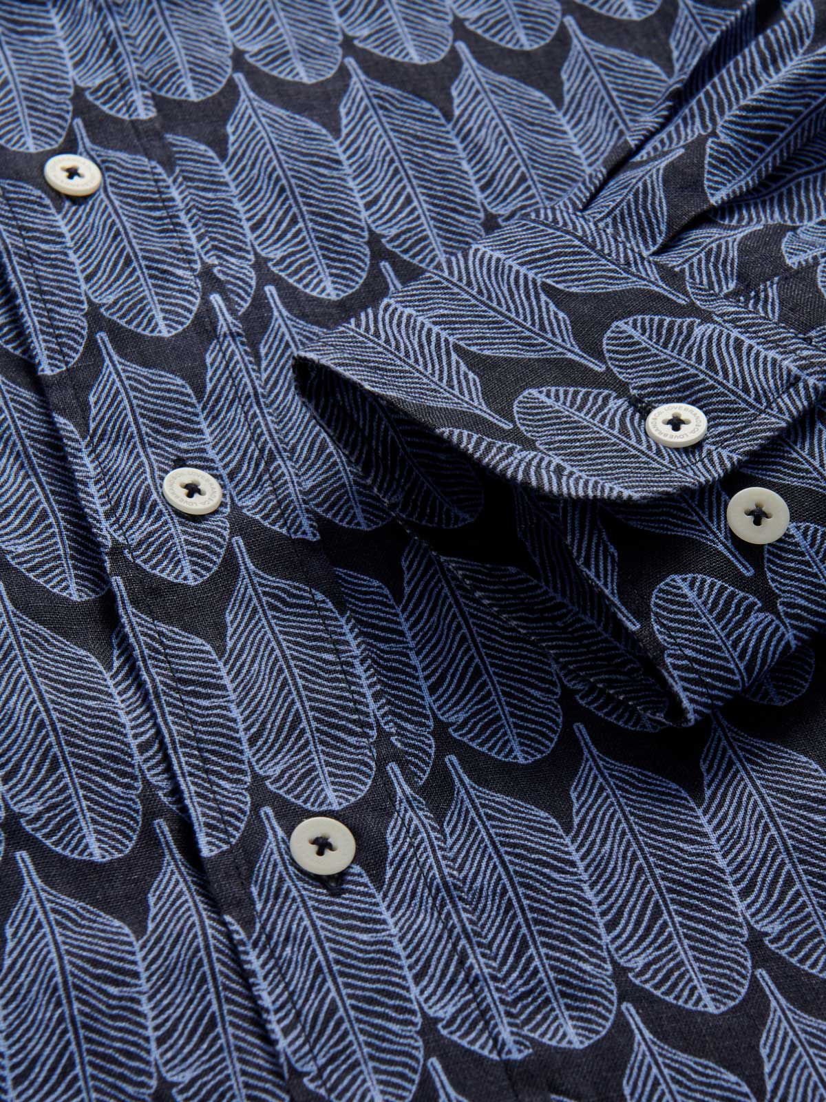 Cuff view of men's gone bananas abaco linen shirt. Blue tropical print shirt with corozo nut buttons.