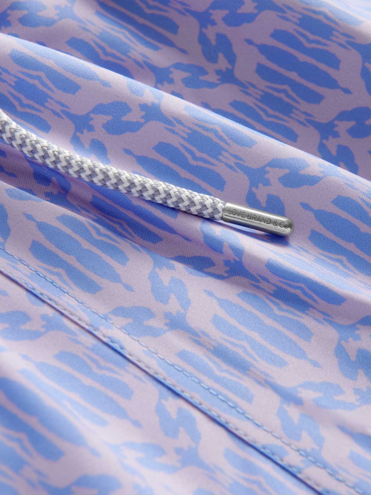 Men's Head in the Clouds Staniel Swim Shorts featuring a giraffe geometric print in pastel lavender and blue hues with a back pocket detail.