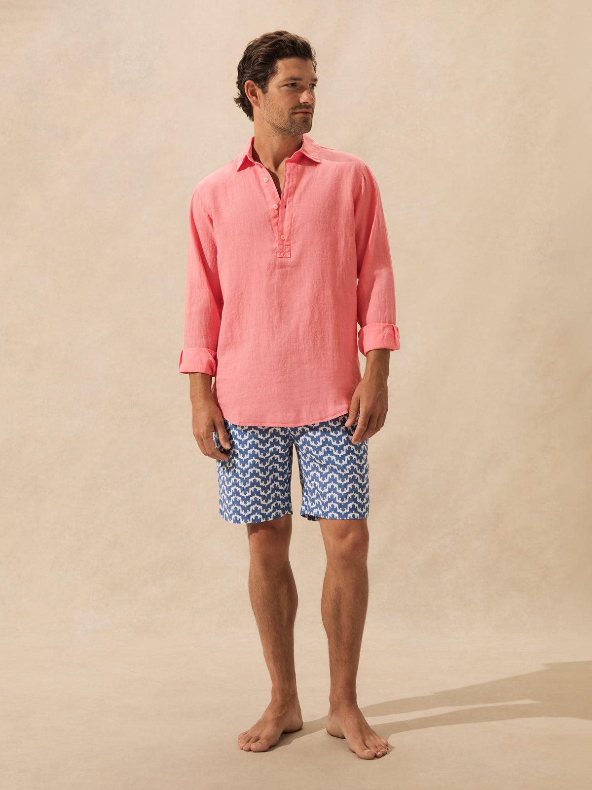 Man wears pink long sleeve shirt with blue elephant shorts.