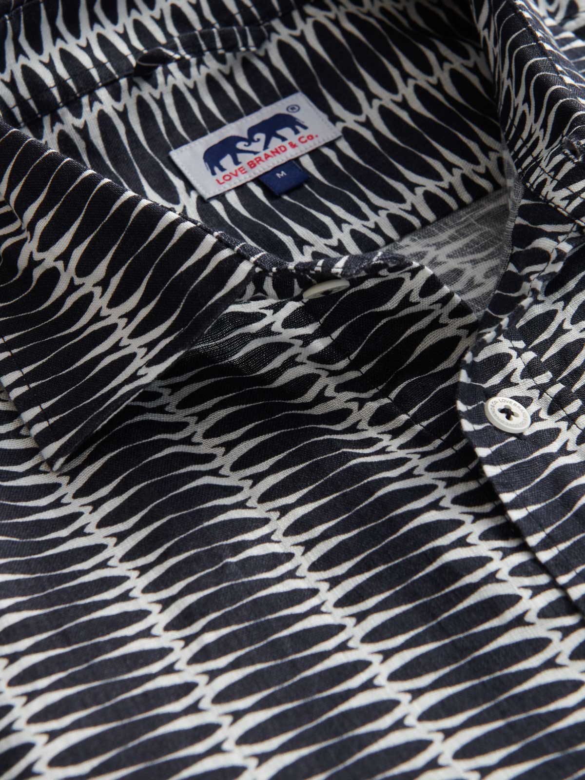 Close-up view of men's silly sardines abaco linen shirt. Detailed shot showing the sardines print in navy blue and white.