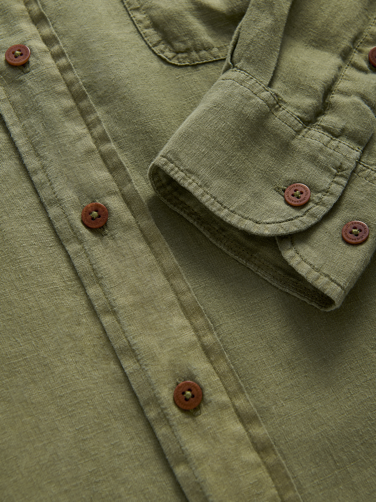 close-up view of the cuff of an olive green hemp shirt