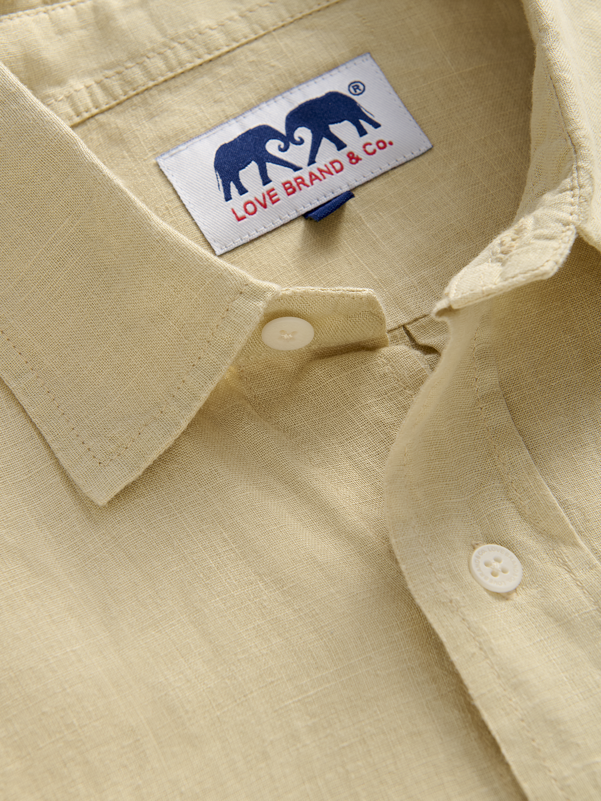 collar view of a beige hemp shirt with a love brand label featuring 2 elephants