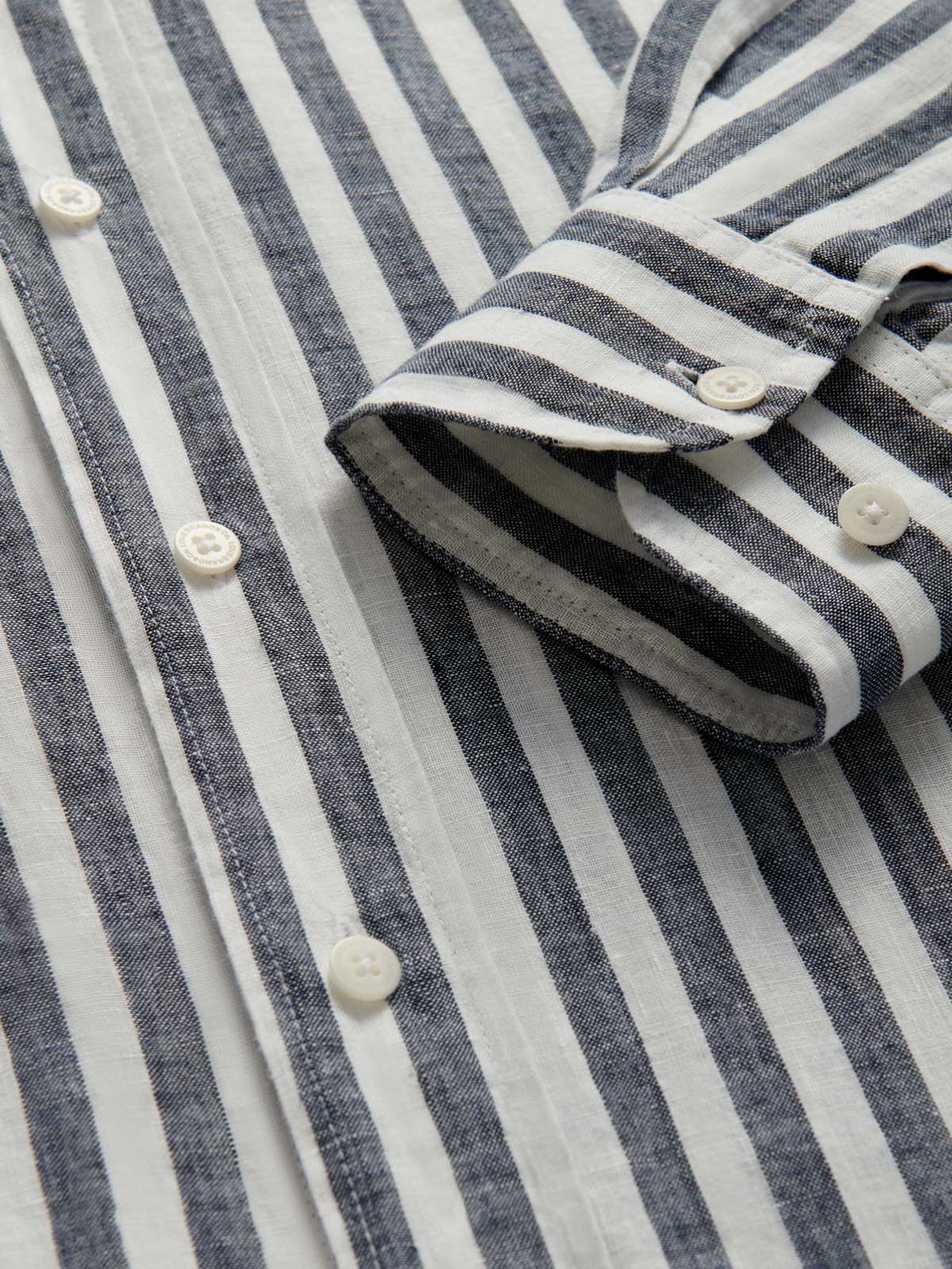 Close-up cuff view of mens navy striped linen shirt. White and navy blue stripes on 100% linen.