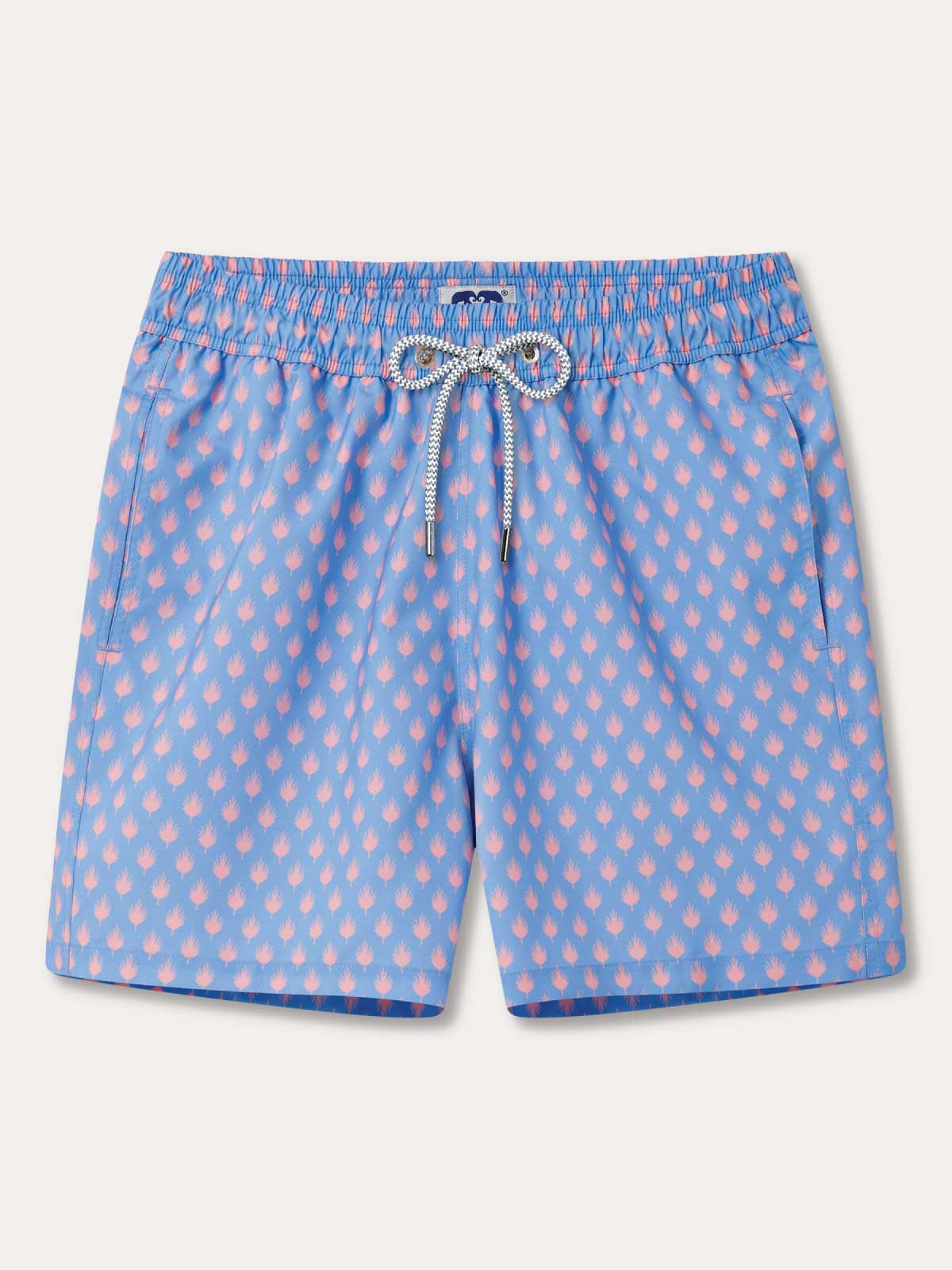 Blue swim shorts with pink palm leaf pattern on a light grey background