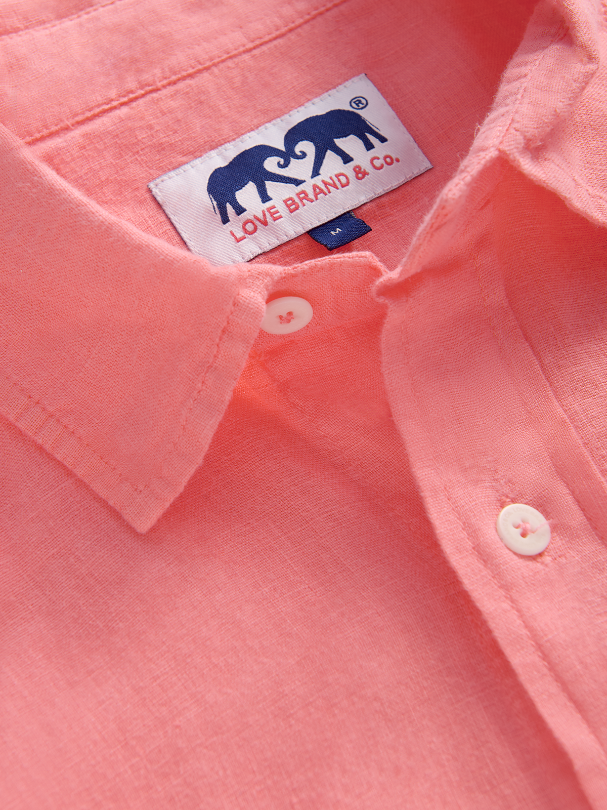 Close-up of a pink shirt with a brand label featuring two elephants.