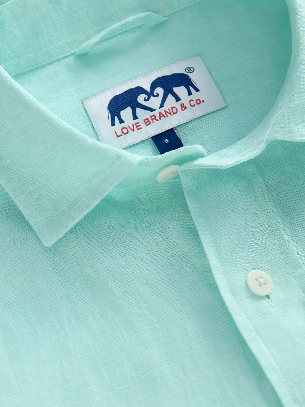 Close-up of a light green/blue linen shirt with a visible love brand label.