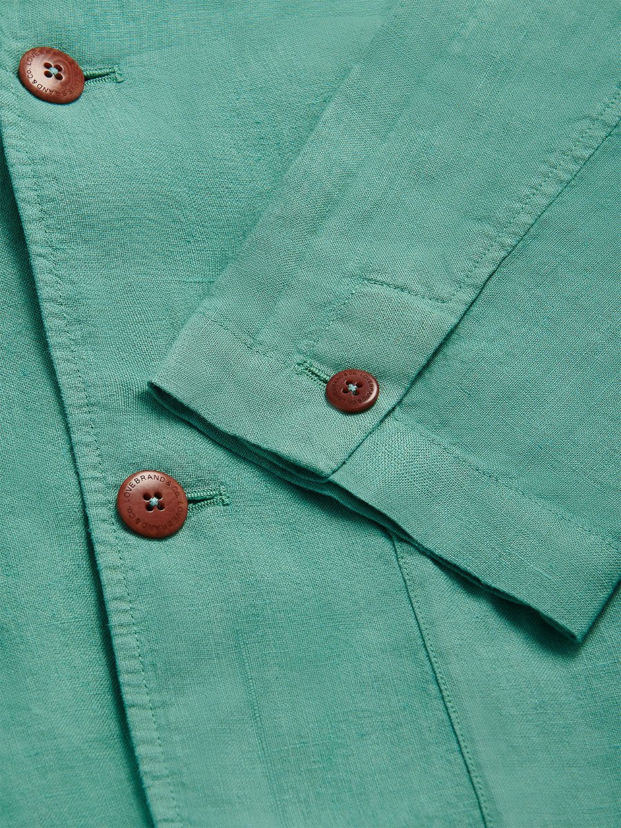 Close-up of Men's Riviera Green Nassau Linen Jacket with corozo nut buttons. Rich green fabric exuding old money style.