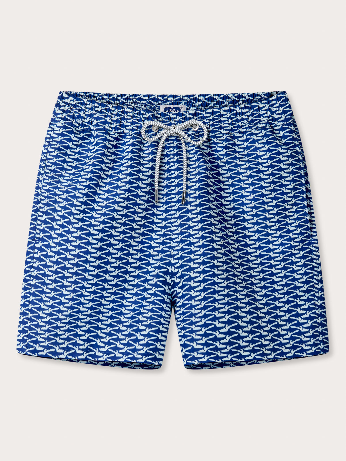 Blue swim shorts with white shark pattern on a light grey background
