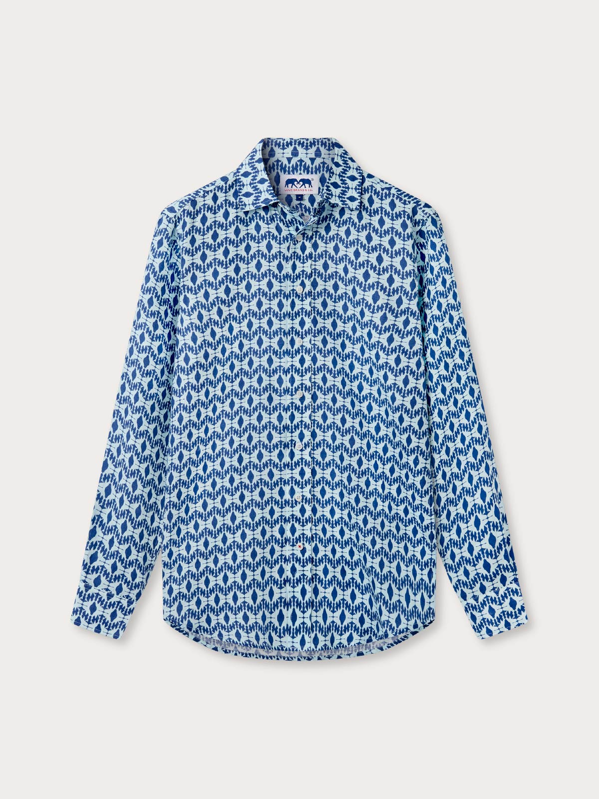 Blue patterned shirt with shark design on a light grey background. Front view of long-sleeved button-up blue linen shirt.