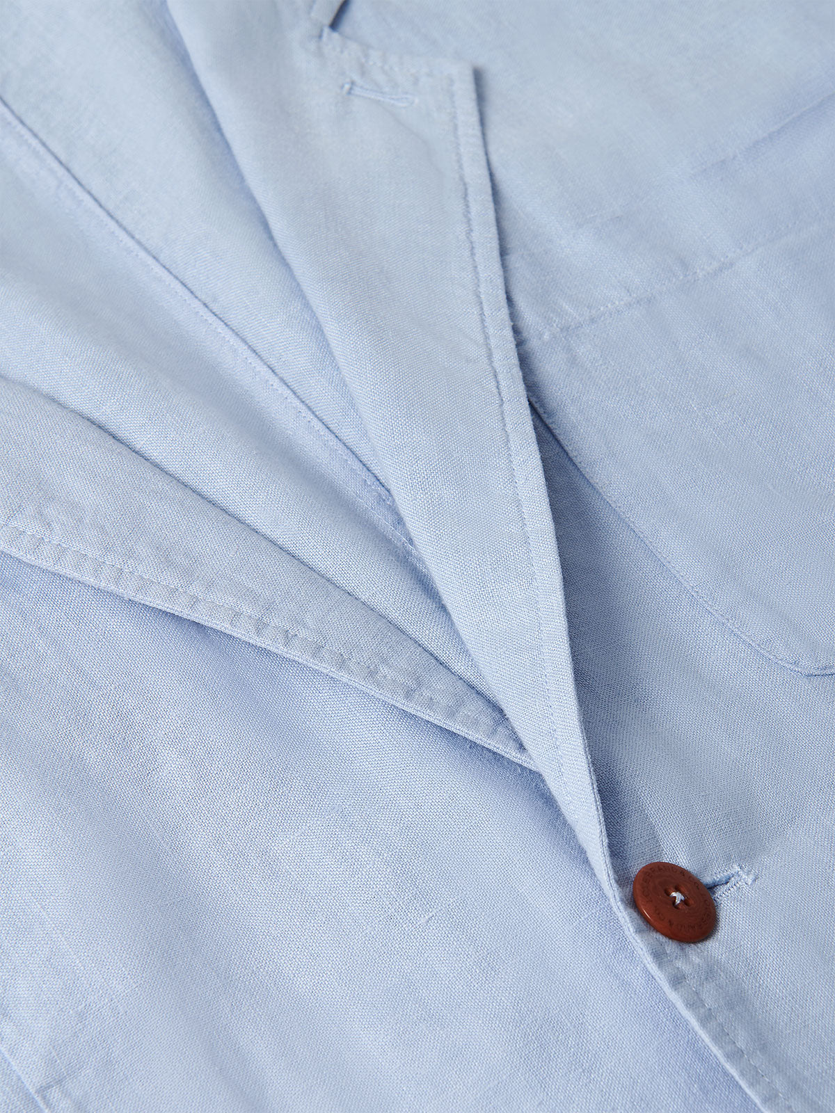 Close-up view of Men's Sky Blue Nassau Linen Jacket fabric and wooden button detail.
