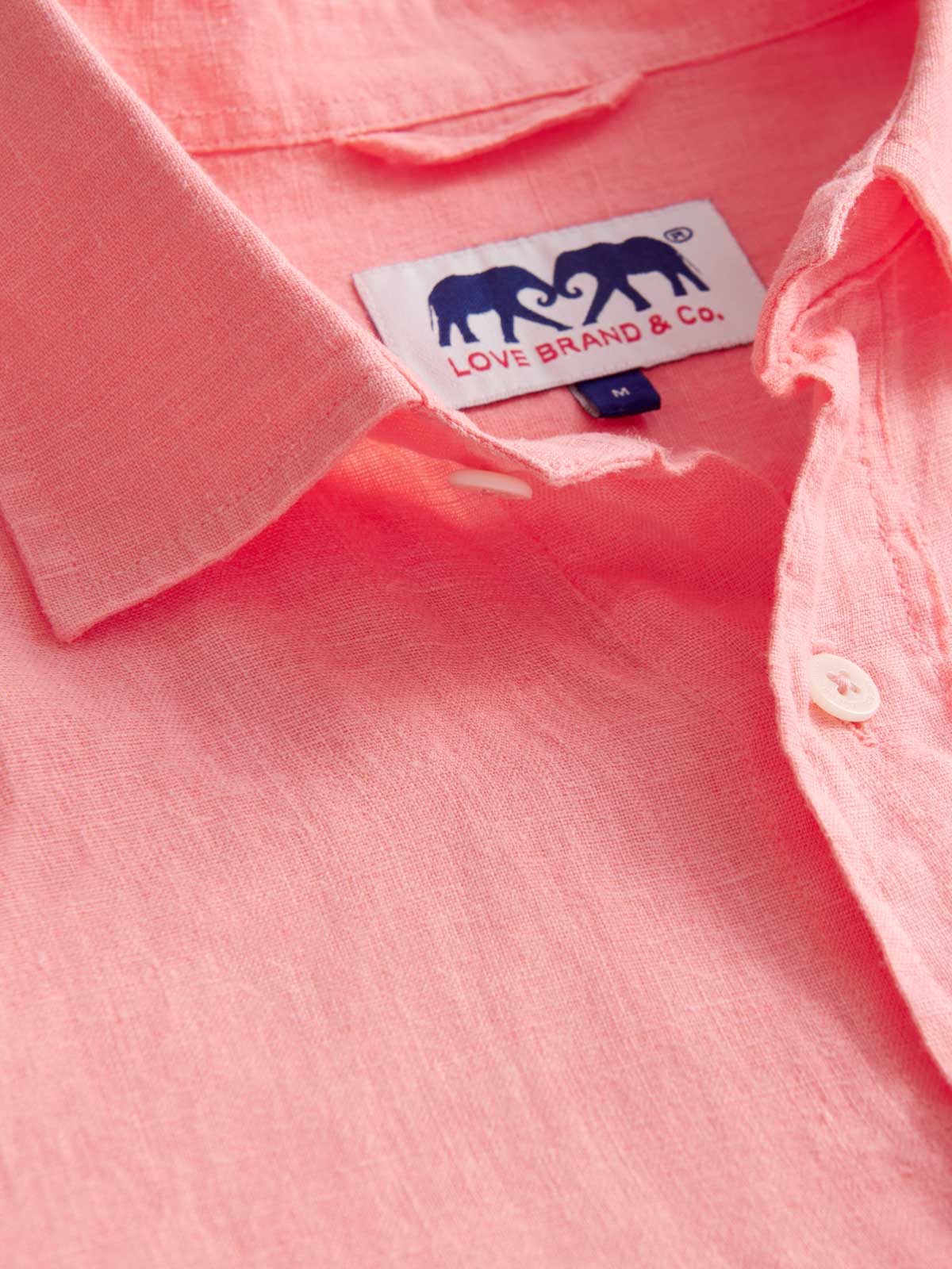 Close-up view of Men's Watermelon Abaco Linen Shirt. Pink men's shirt showing classic collar and logo label.