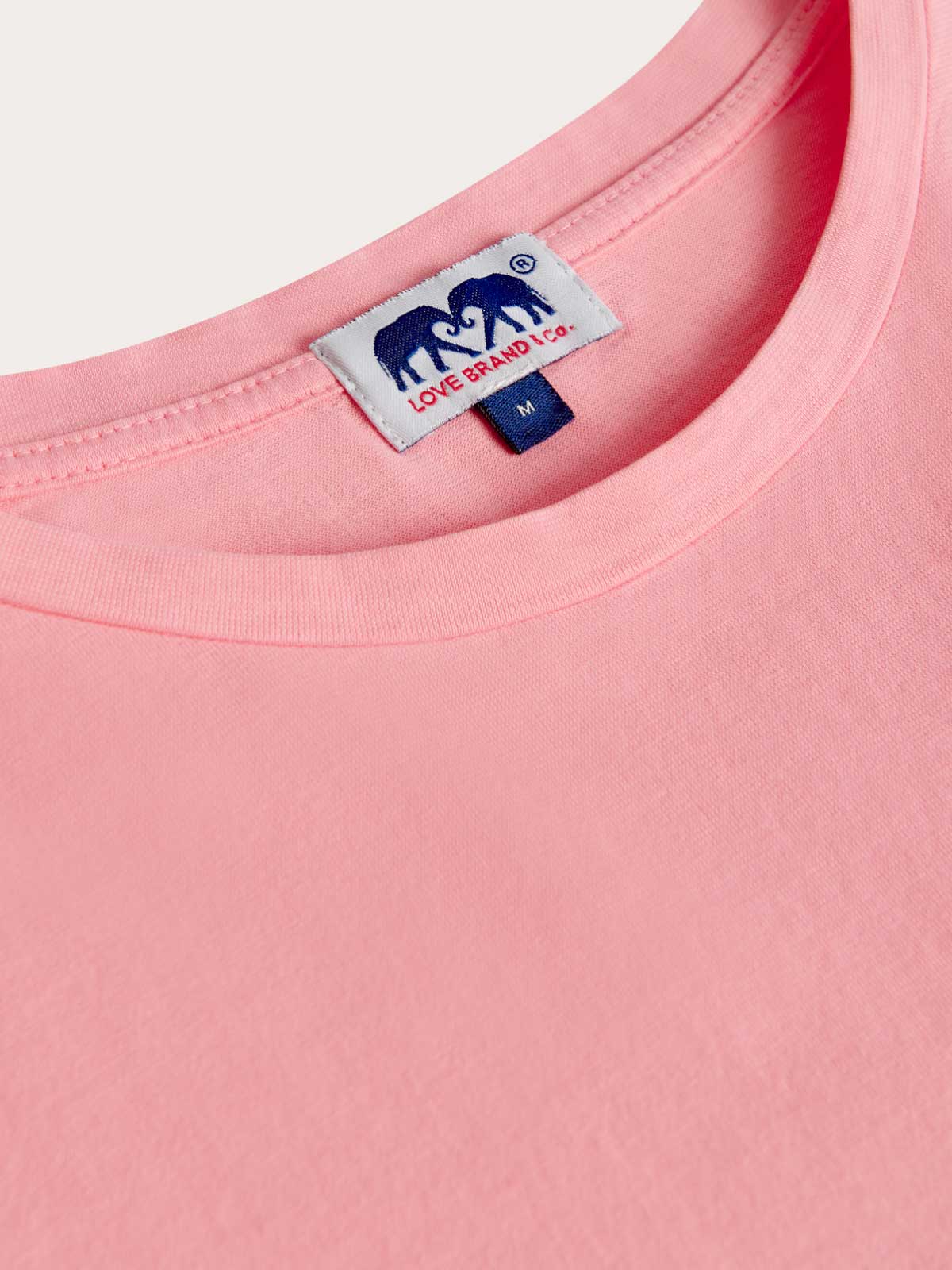 Men's Watermelon T-shirt by Love Brand. Close-up view of the collar of this mens t-shirt showcasing love brand label and the pink cotton fabric.