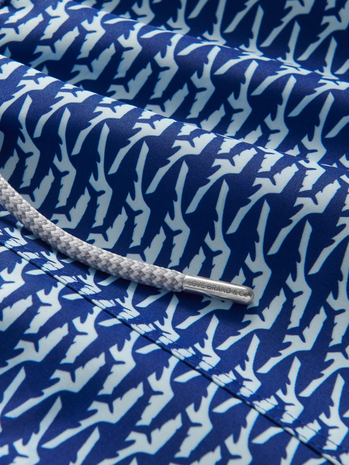 Close-up of a blue fabric with white shark pattern and a drawstring tie.