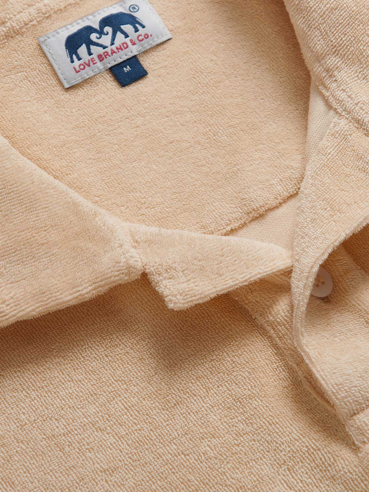 Close-up view of Men's Coconut Powell Terry Polo. Brown terry towelling polo shirt crafted from 100% cotton. Short-sleeved polo shirt.