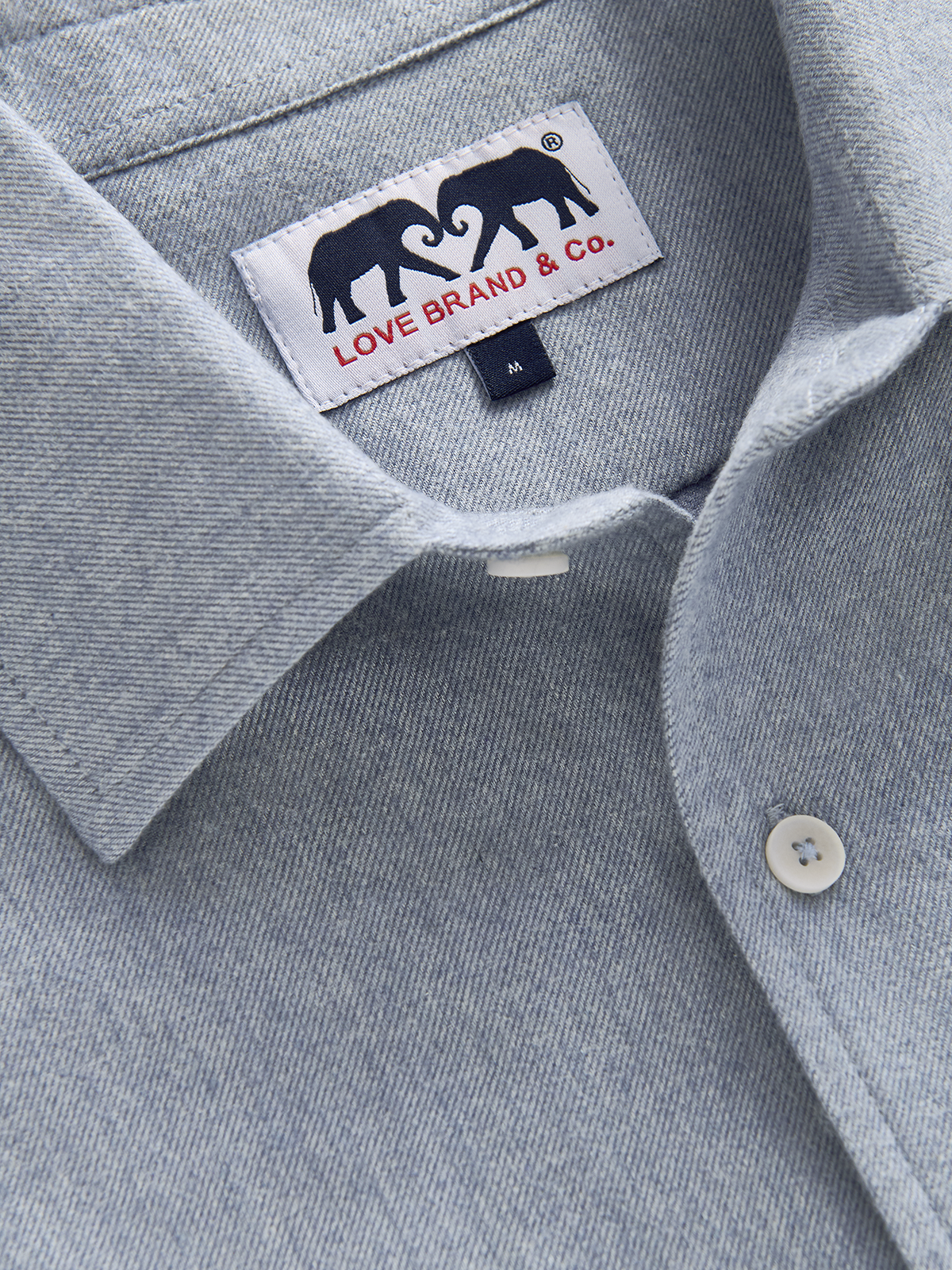 Close-up of a light blue textured button-down shirt collar with a visible Love Brand & Co. neck label and white buttons.