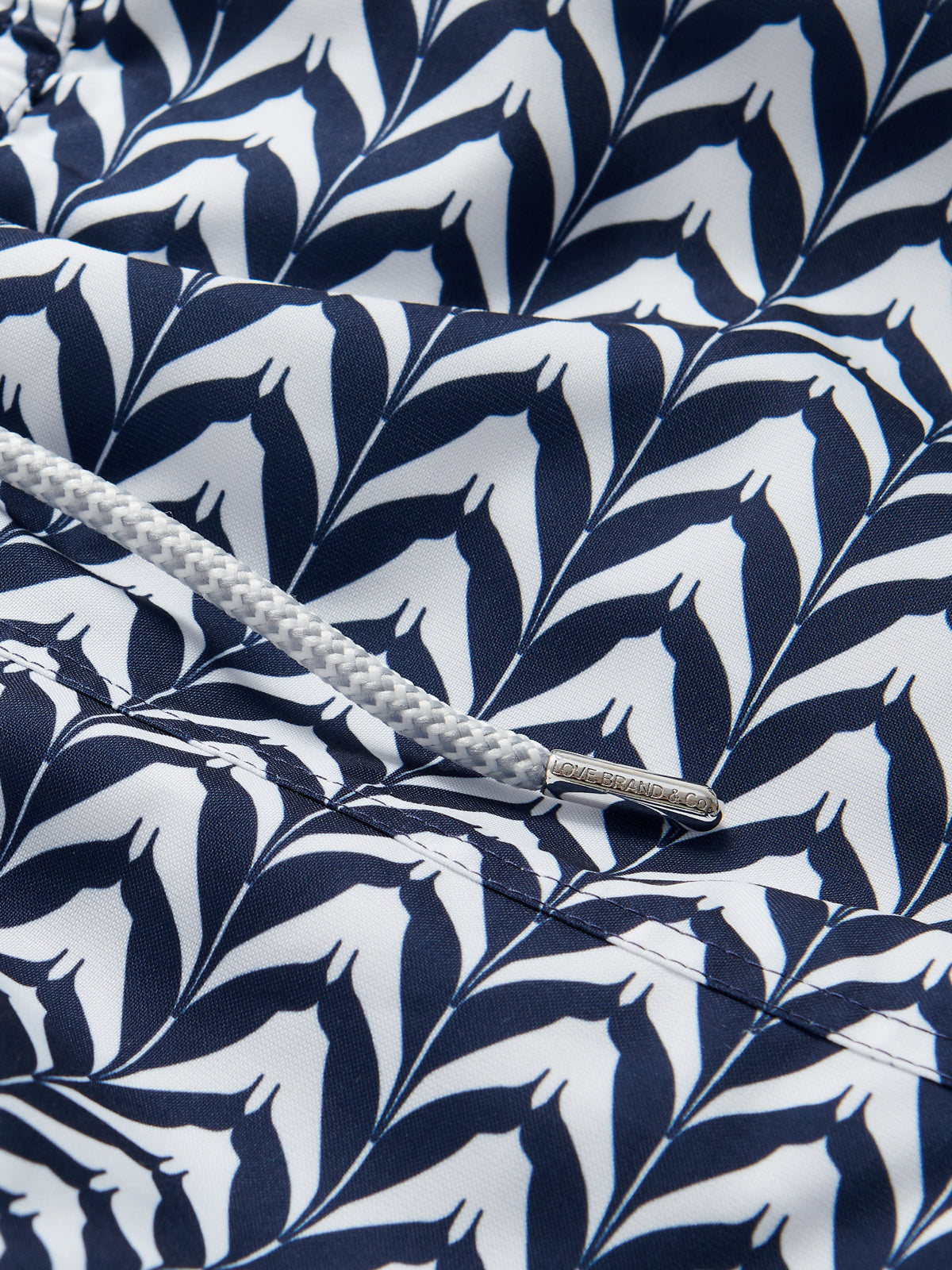 Close-up of Men's Feather Icing Staniel Swim Shorts fabric showcasing blue and white feather pattern and drawstring detail.