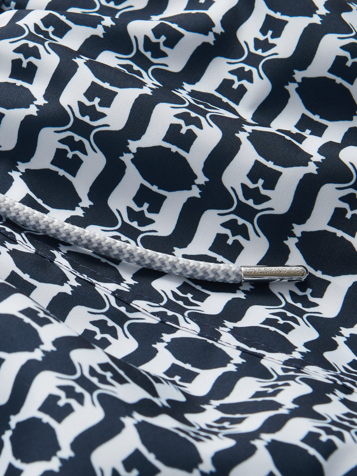 Close-up view of "Men's on The Prowl Staniel Swim Shorts" featuring rhythmic geometric patterns in navy blue and white inspired by the Florida Panther.
