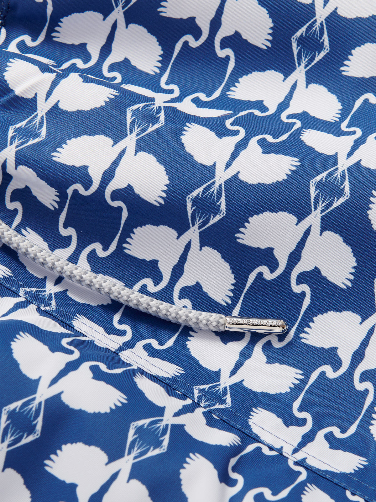 Close-up view of Boys White Heron Staniel Swim Shorts by LOVE BRAND & Co., featuring a blue and white Great White Heron print, designed for The Boca Raton resort.