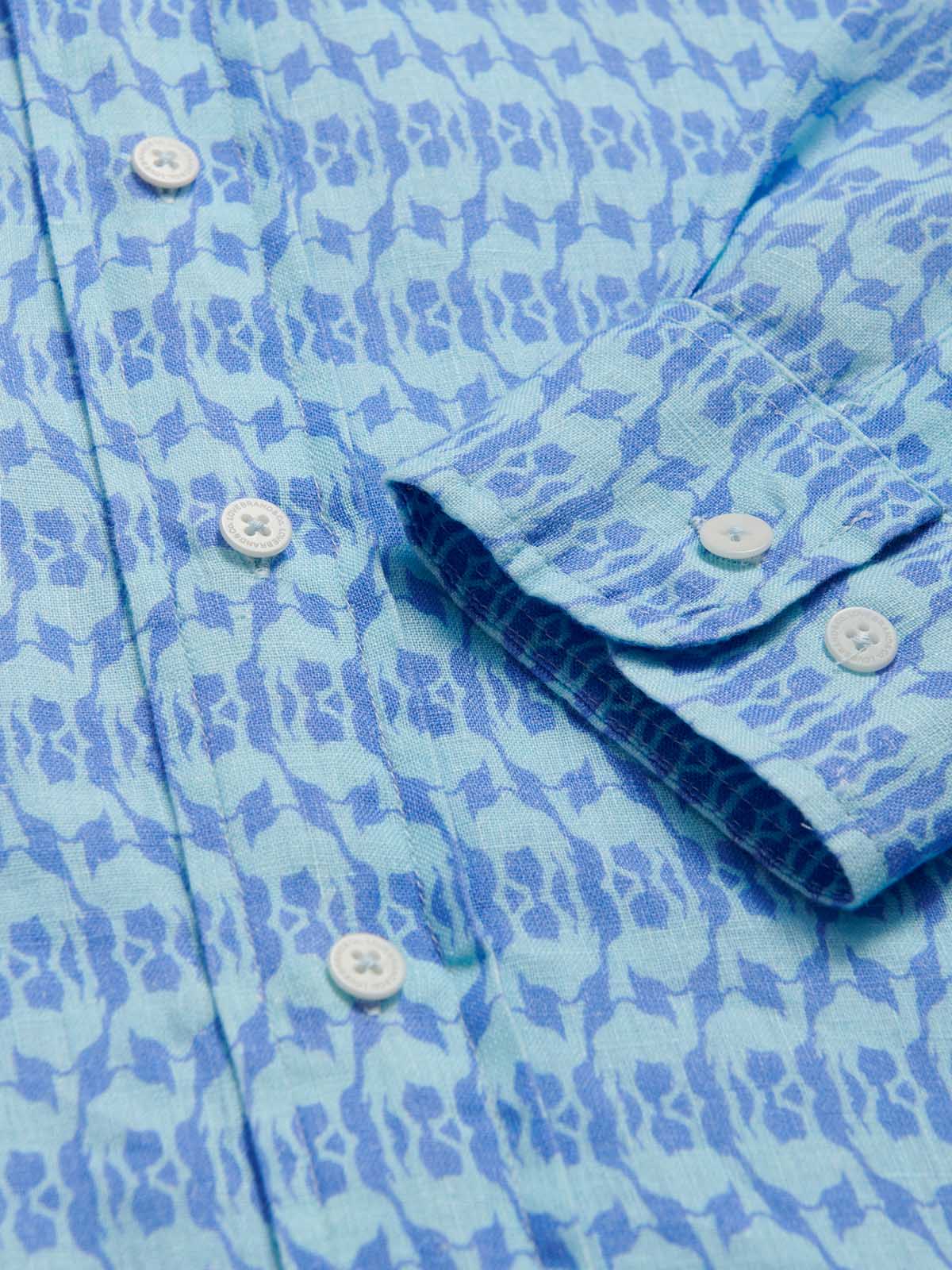 Close-up of the Men's Camel Mirage Sky Abaco Linen Shirt, showcasing its detailed blue patterned fabric and white buttons. Old money shirts made from 100% linen.
