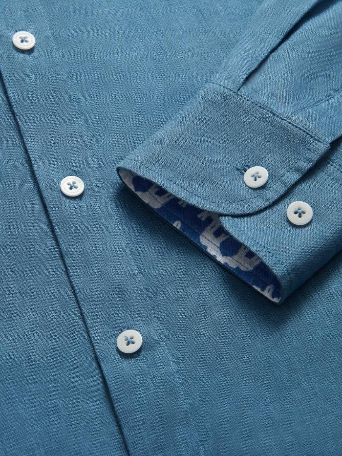 Close-up of a Men's Elephant Palace Blue Maycock Linen Shirt, showcasing the folded-back cuff with an exclusive elephant print and signature corozo nut buttons.