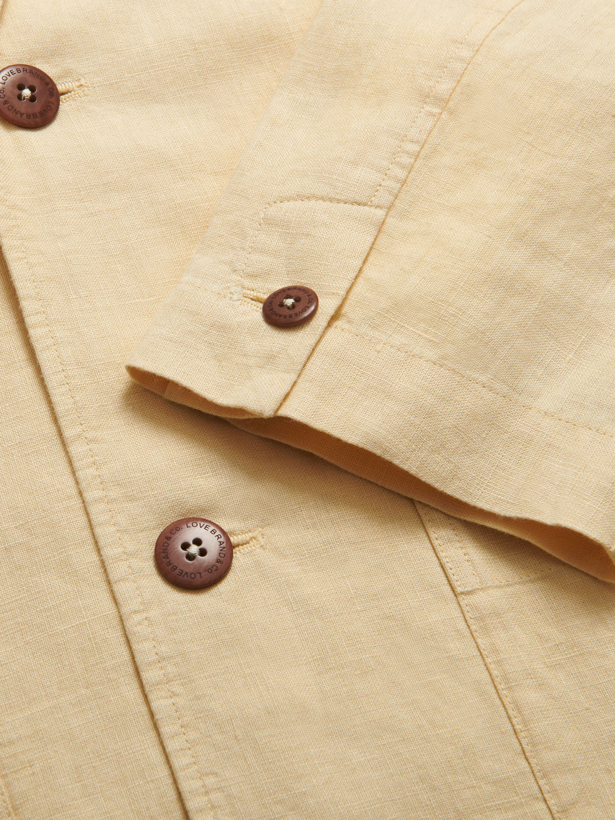 Close-up of Men's Stone Nassau Linen Jacket. Men's linen jacket highlighting the brown corozo nut buttons and fine 100% light linen fabric.