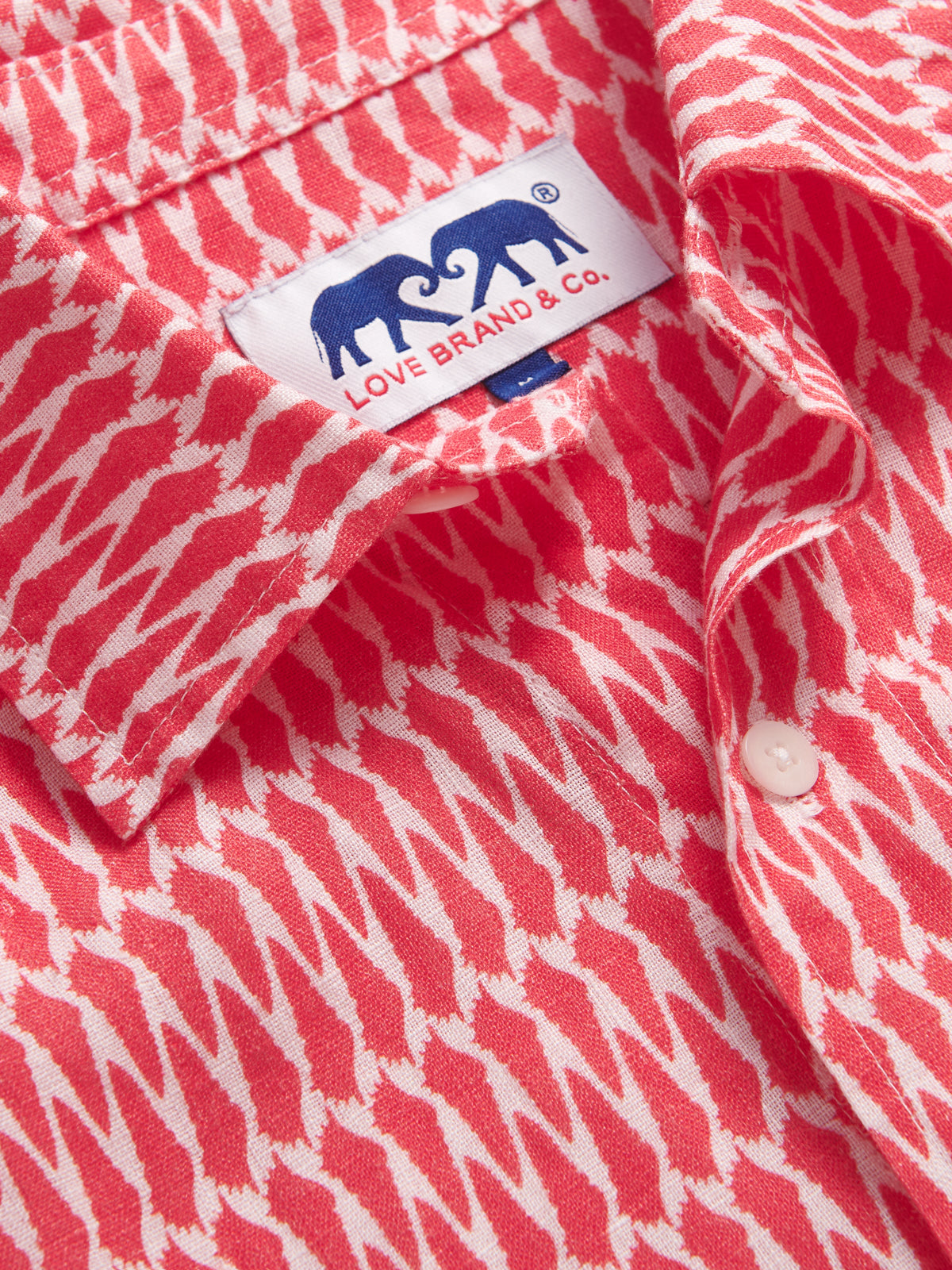 Close-up view of Men’s Hot as Shell Abaco Linen Shirt showcasing Love Brand & Co. logo and conch shell pattern.