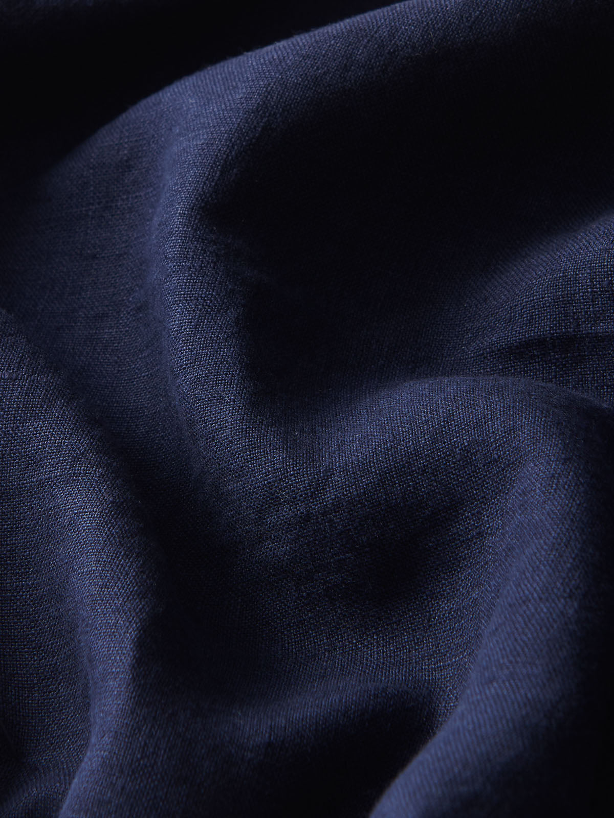 Close-up view of Men's Navy Blue Eleuthera Linen Trousers. Navy blue linen pants for men with 2 front pockets and drawstring waist in a relaxed fit.