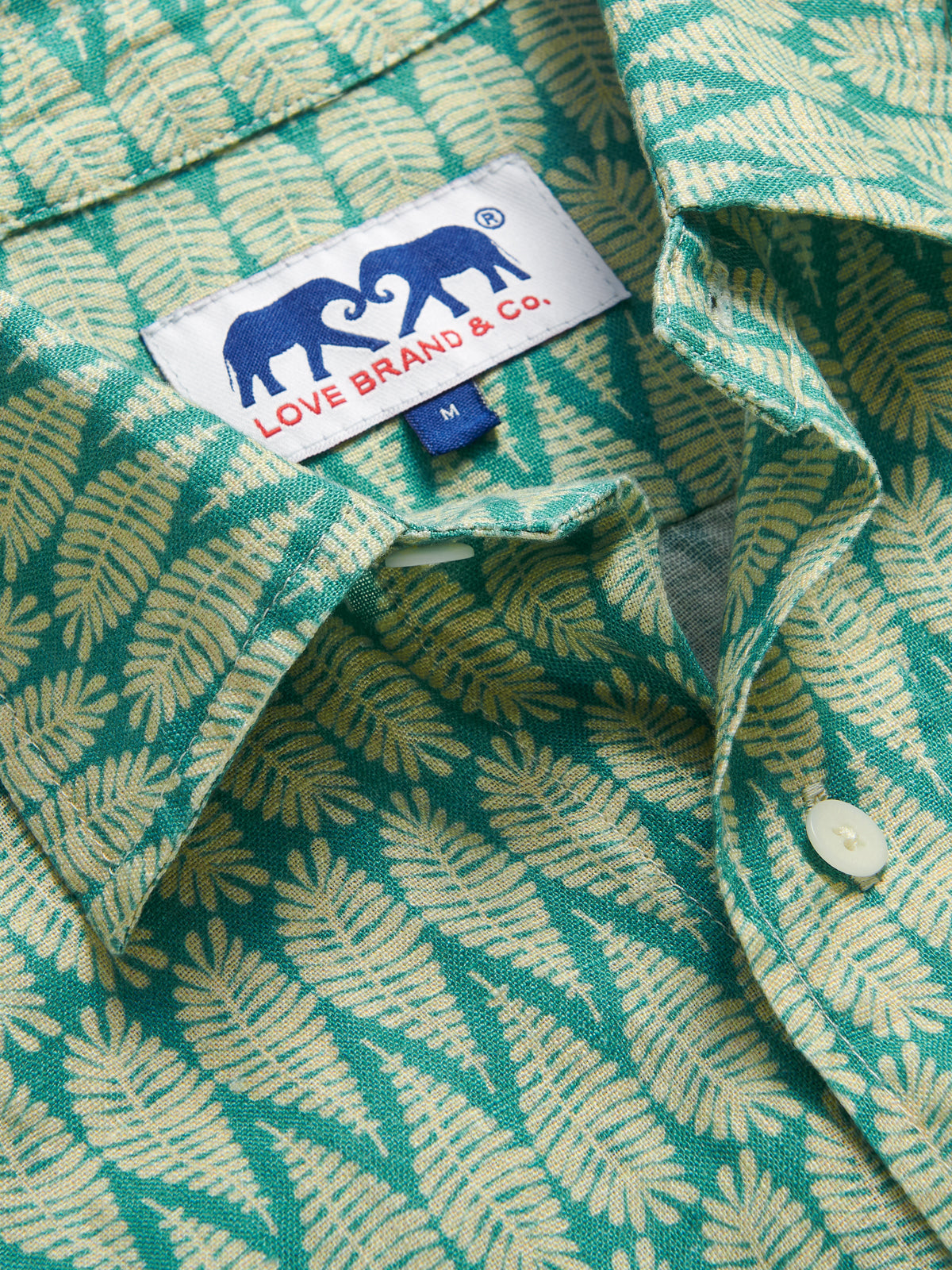 Close-up view of Men's Paradise Abaco Linen Shirt. Men's green shirt with gold leaf print.